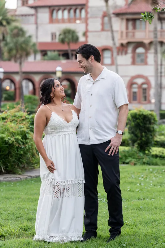 Dana and Christian stand facing each other on a lawn with a pink historic building behind them in downtown St Augustine.