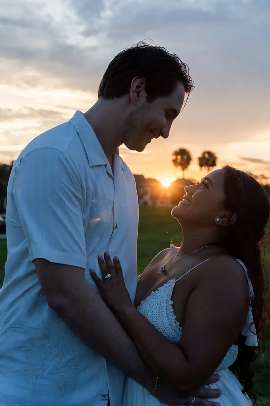 Christian looks down at Dana as golden light from the setting sun frames them both during an intimate moment.