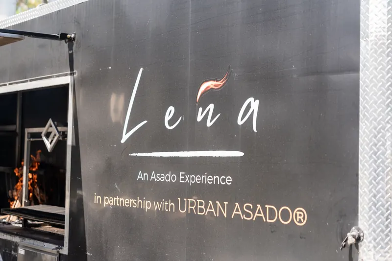 Lena Asado Experience sign on dark metal structure advertising partnership with Urban Asado.