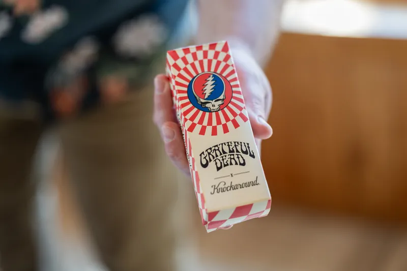Someone holds a red and white Grateful Dead-themed wedding favor box at the reception.