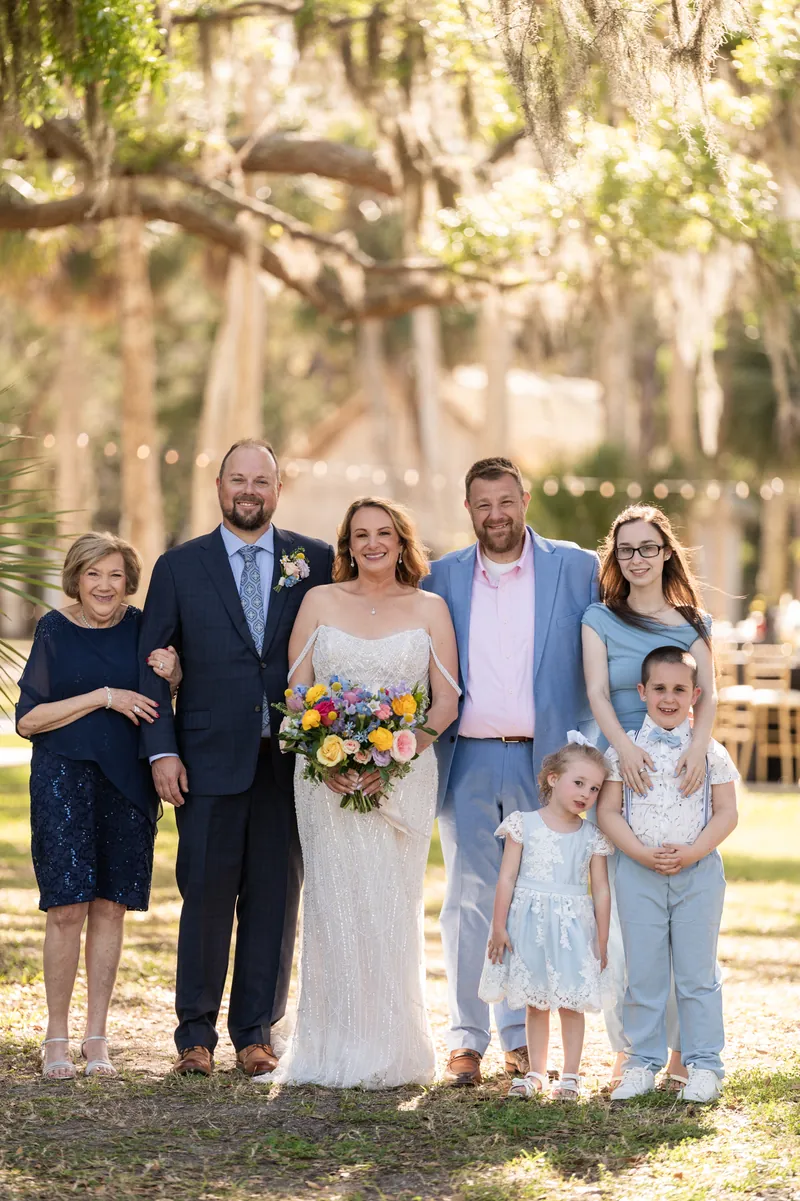 Von and Danielle stand with family members, including children, on a sandy path surrounded by moss-draped trees.