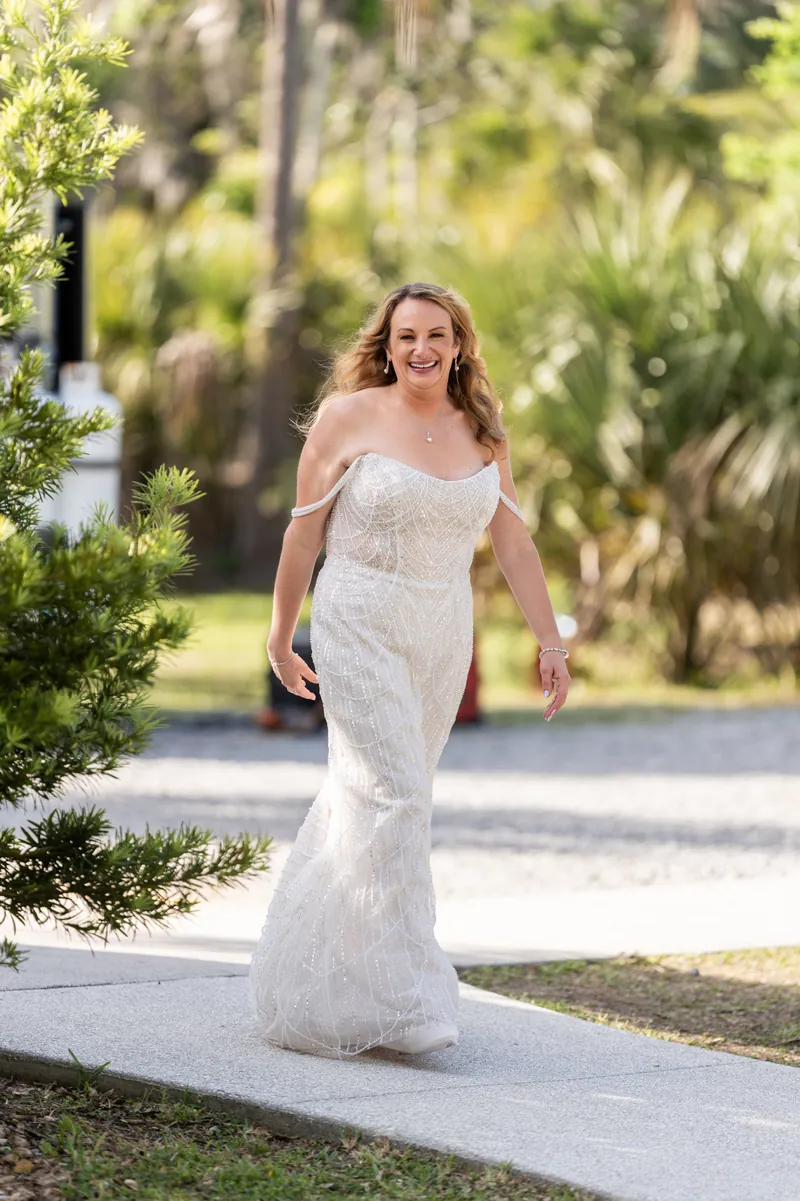 Danielle walks down tree-lined path in off-shoulder ivory mermaid wedding dress with beaded details.