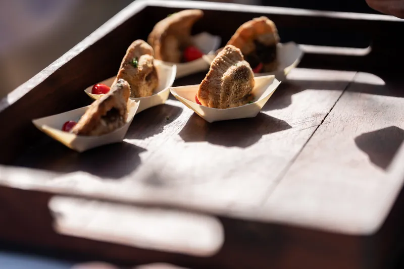 Three small sandwich appetizers arranged on a white plate in sunlight.