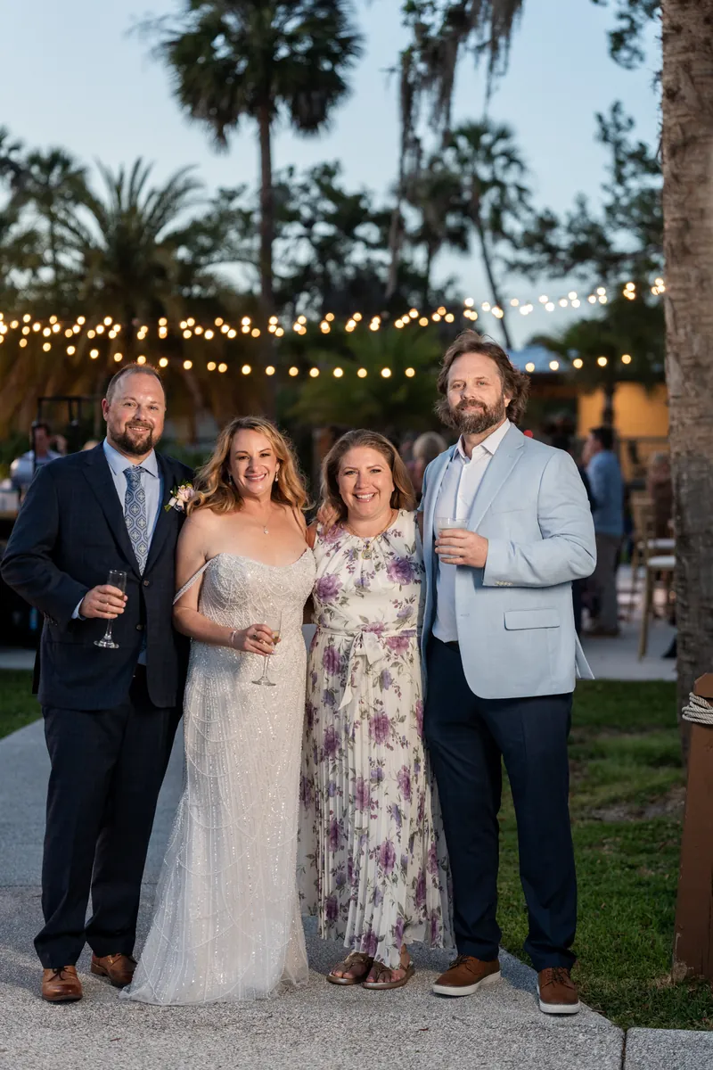 Von, Danielle, and two guests stand together at dusk under strung market lights in a garden setting.