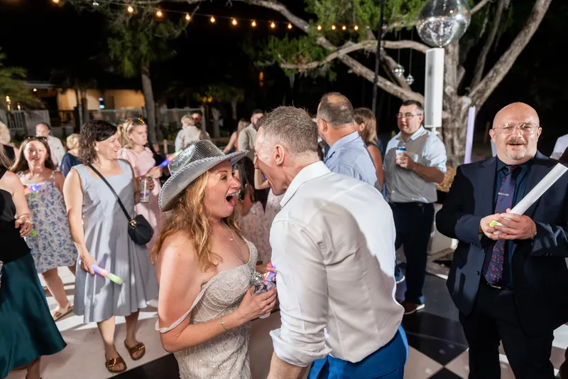Guests dance and celebrate together on the outdoor dance floor under string lights at night.