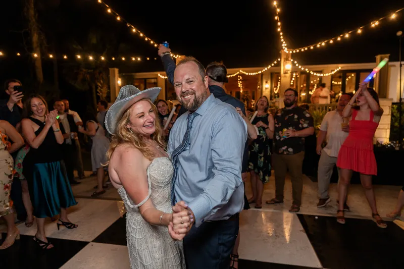 Von embraces Danielle on the dance floor as string lights glow overhead during their outdoor wedding celebration.