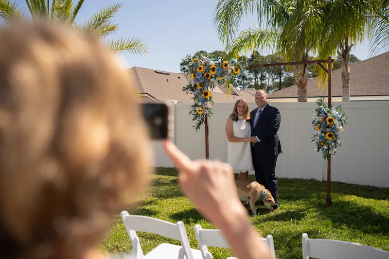 Someone photographs the couple exchanging vows at the altar as they stand together on the grass.