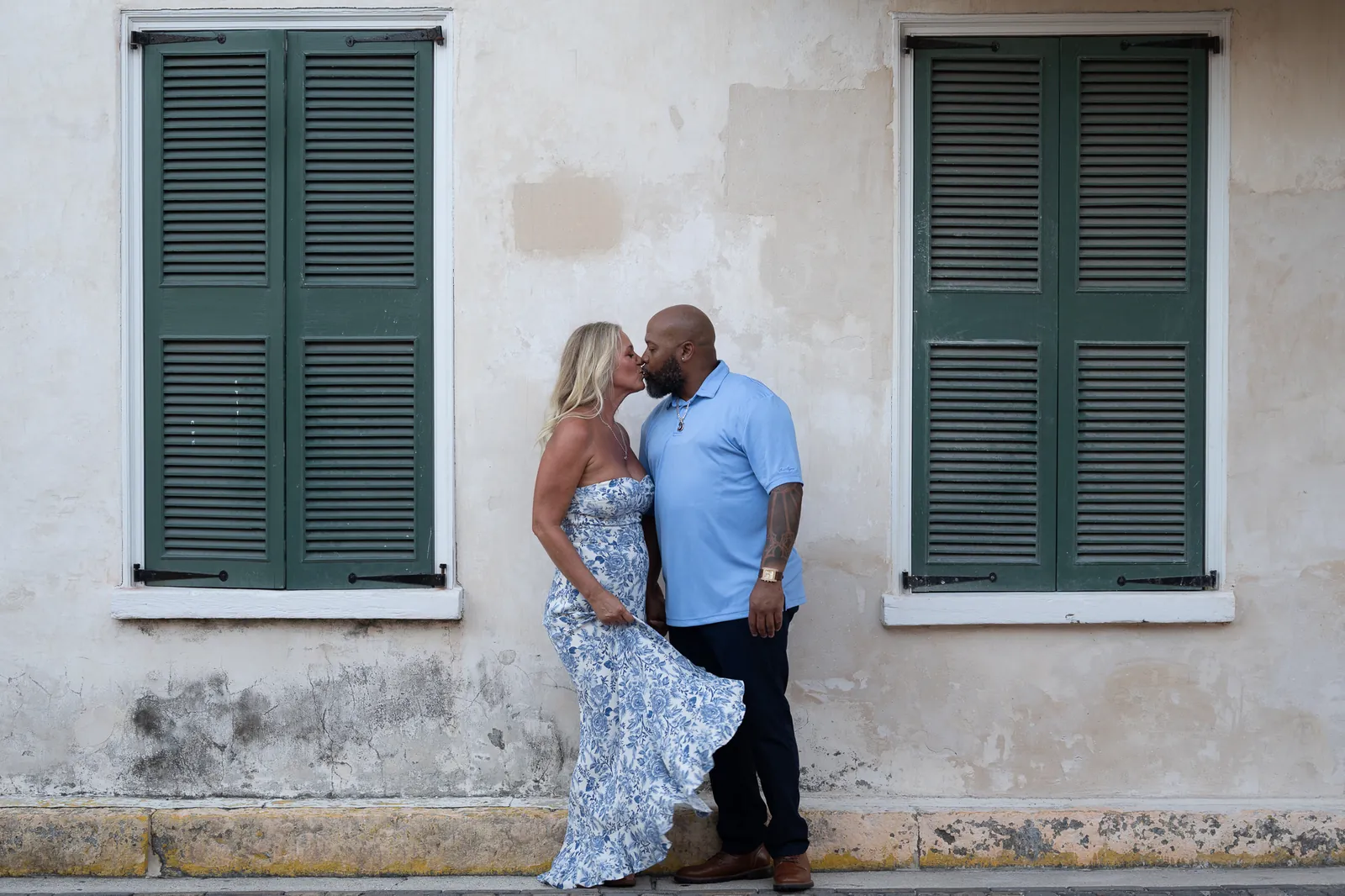 Dee and Tonya kissing against historic building with green shutters