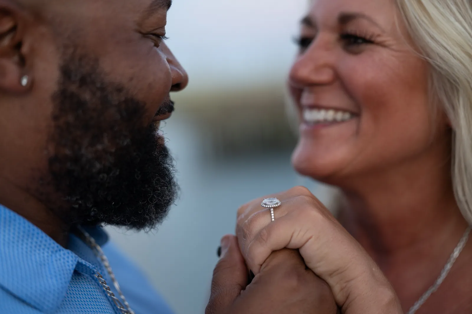 Close-up of engagement ring with couple smiling