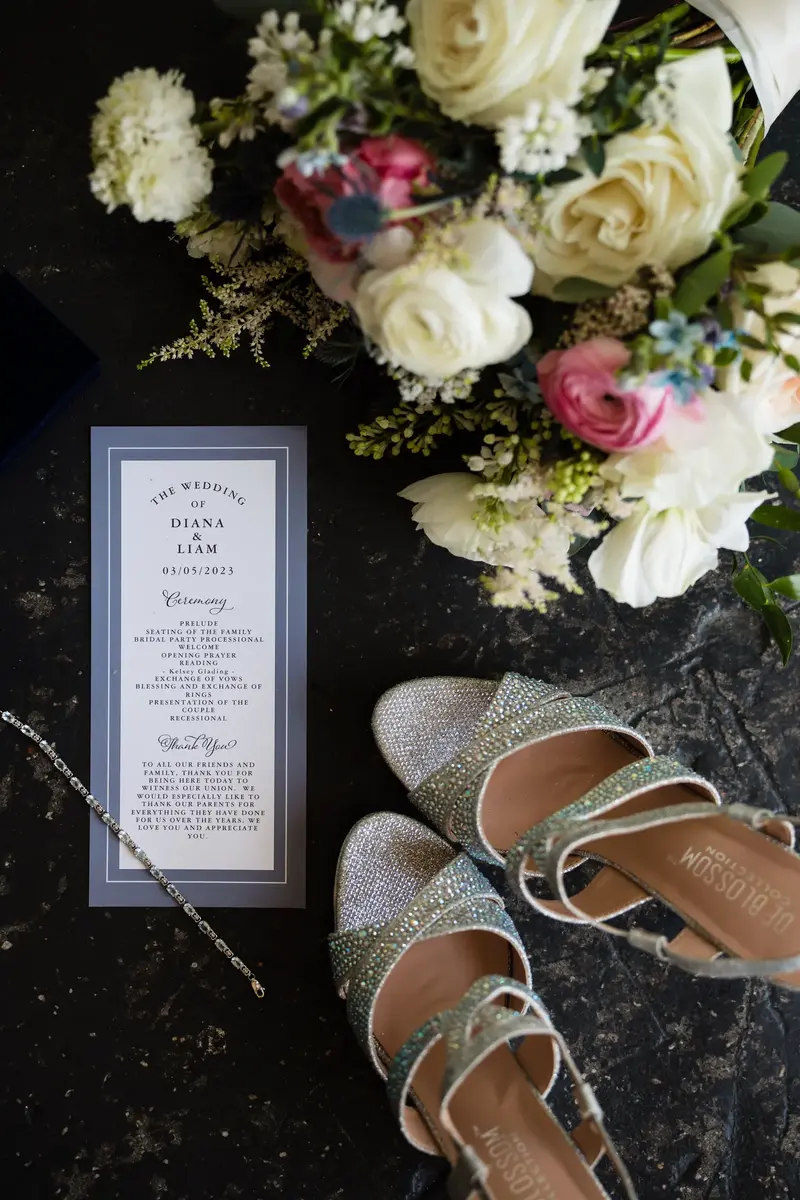 Wedding day flat lay with ceremony program, sparkly shoes, and bouquet