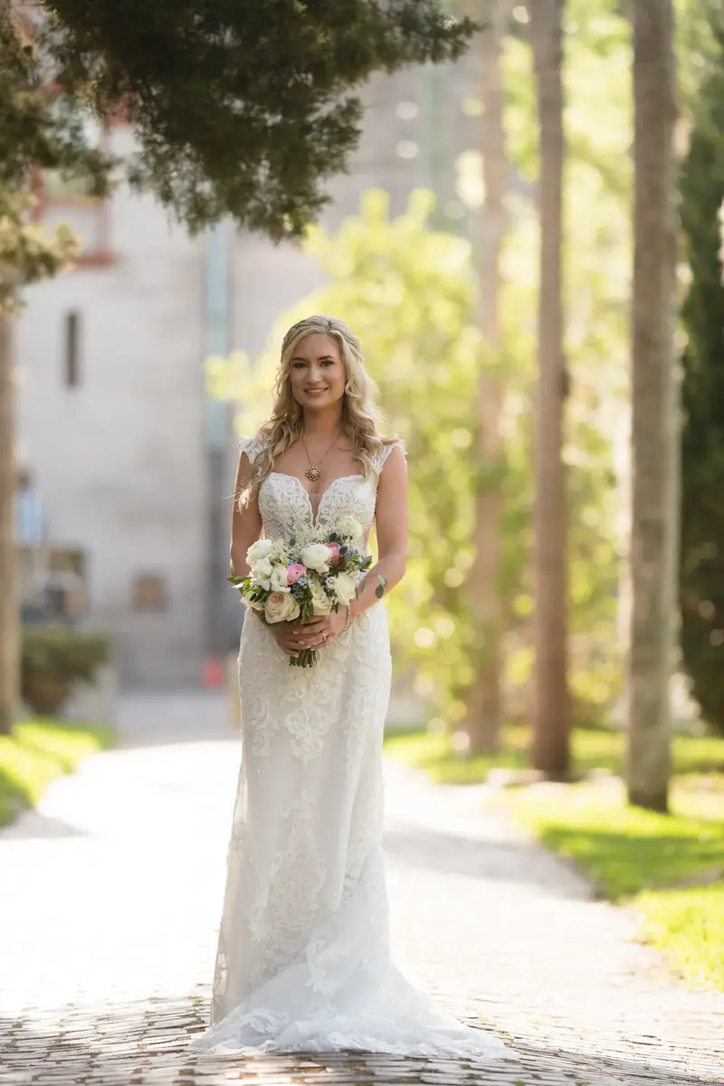 Bridal portrait in sunlit pathway holding bouquet
