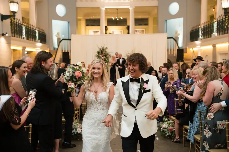 Newlyweds walking back up the aisle as guests cheer