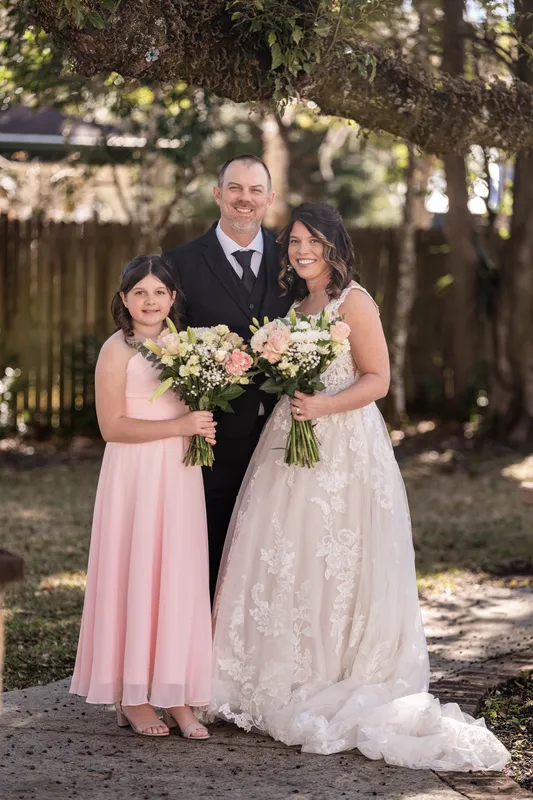 Family portrait of all three holding bouquets under an oak tree