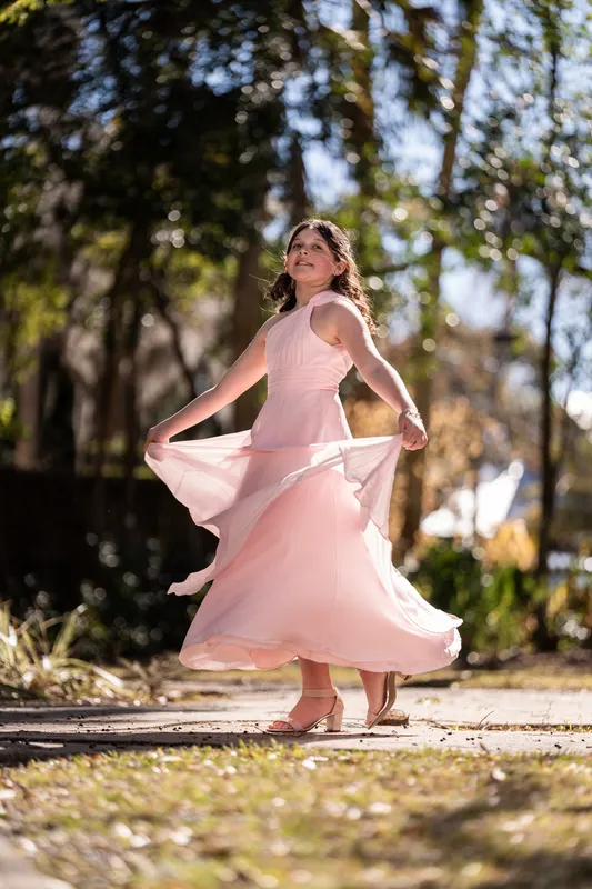 Their daughter twirling in her pink dress on the sidewalk