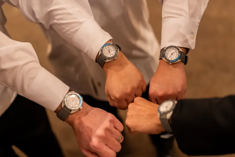 Groomsmen showing off matching watches in a fist bump