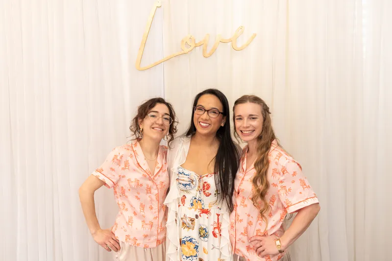 Bride with bridesmaids in matching pajamas under gold Love sign