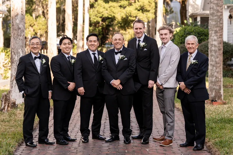 Groom with groomsmen and family on a brick pathway under Spanish moss