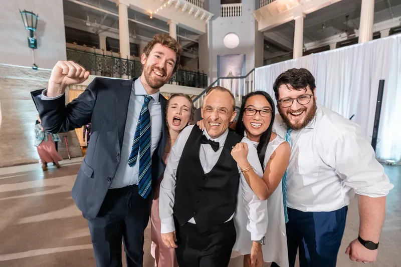 Five guests grin and raise their fists in celebration inside the Lightner Museum's spacious indoor venue.