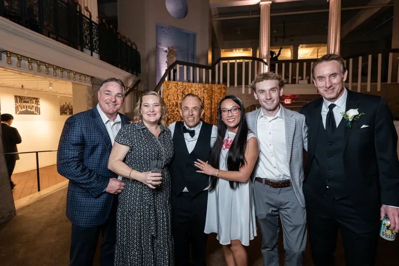 Six family members pose formally in dress attire on the illuminated floor of the historic venue.