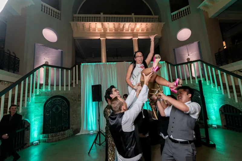 Jason and Elizabeth celebrate mid-air with family members beneath the museum's ornate balcony.