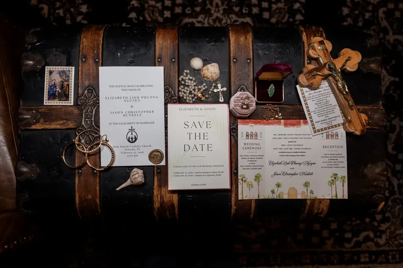 Save-the-date cards and wedding stationery arranged on a vintage suitcase with decorative details.