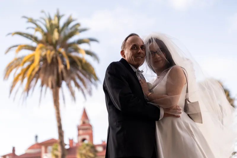 Bride and groom portrait with palm tree and Flagler College towers in the background