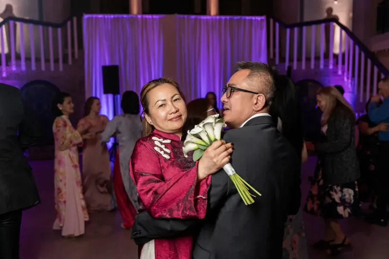 Elizabeth and Jason dance together under purple uplighting at the Lightner Museum while guests celebrate around them.