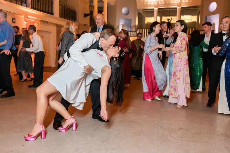 A guest executes an energetic dip on the dance floor at the Lightner Museum as onlookers watch in pink heels.