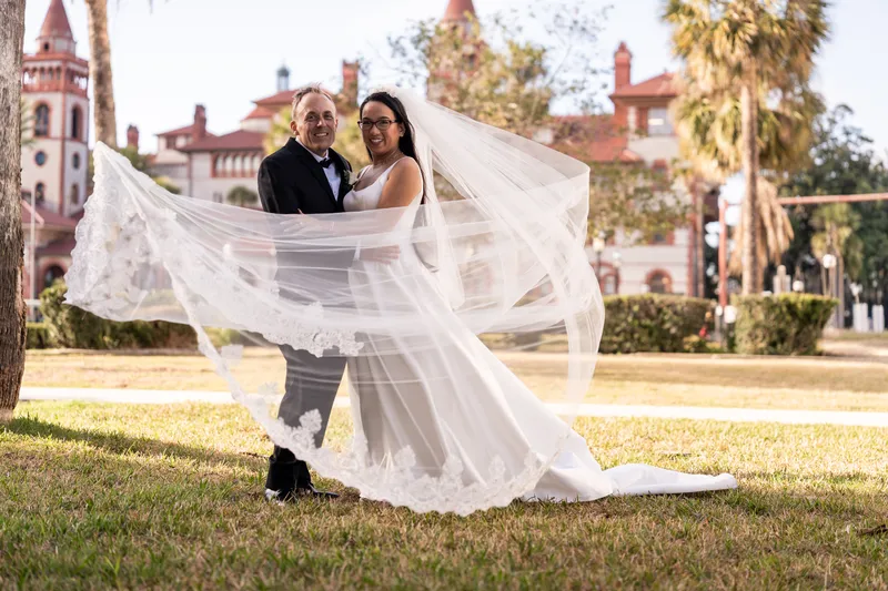 Elizabeth and Jason with her cathedral-length veil billowing wide in front of Flagler College