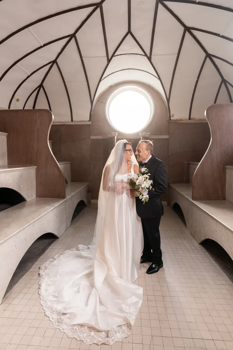 Couple in the Lightner Museum Russian Baths with arched ceiling and veil trailing on the tile floor