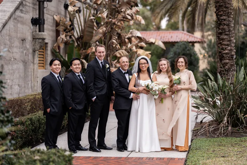 Full wedding party portrait with bridesmaids in ao dai on the Lightner Museum grounds