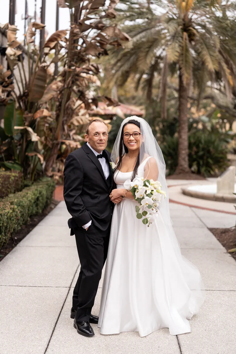 Couple portrait with orchid bouquet among palm trees on the Lightner Museum grounds