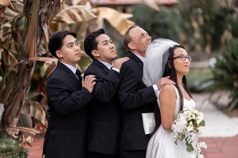 Couple with bride's brothers in a playful dramatic pose on the Lightner Museum grounds
