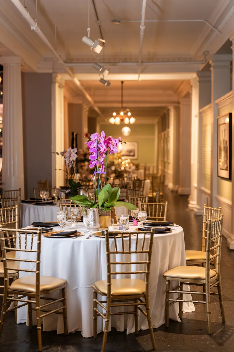Lightner Museum reception room with purple orchid centerpiece and gold chiavari chairs