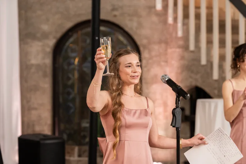 Bridesmaid raising a champagne glass during her toast at the reception