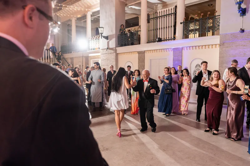 Bride dancing with her father as guests watch and cheer at the Lightner Museum