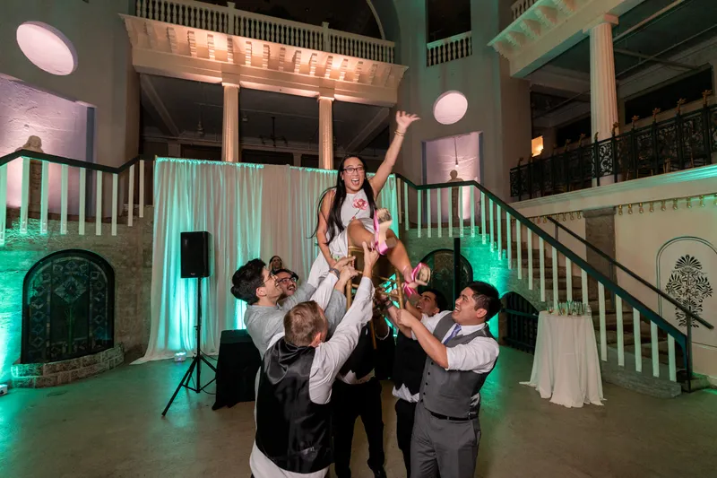 Bride being lifted in the air by guests on the Lightner Museum dance floor