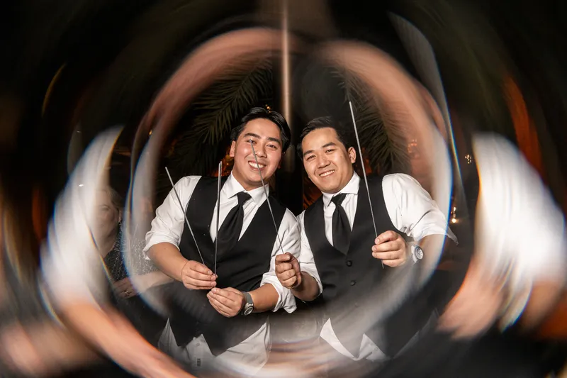 Ring-shot portrait of groomsmen holding sparklers outside the Lightner Museum