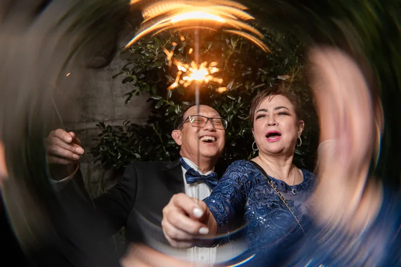 Ring-shot of bride's parents laughing together with a sparkler