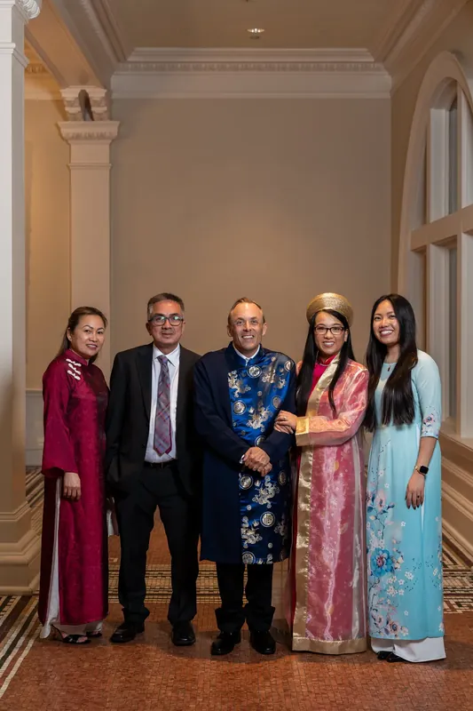 Five family members in jewel-toned traditional South Asian clothing pose together in the Lightner Museum's elegant columned