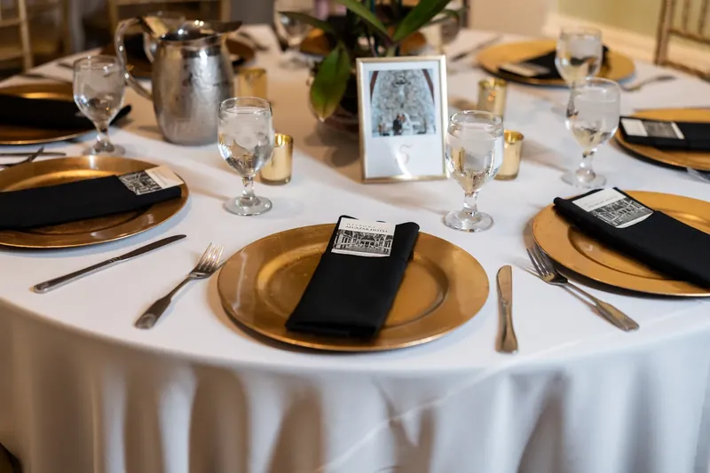 Gold-rimmed chargers and black napkins set an elegant table at Lightner Museum for the reception.
