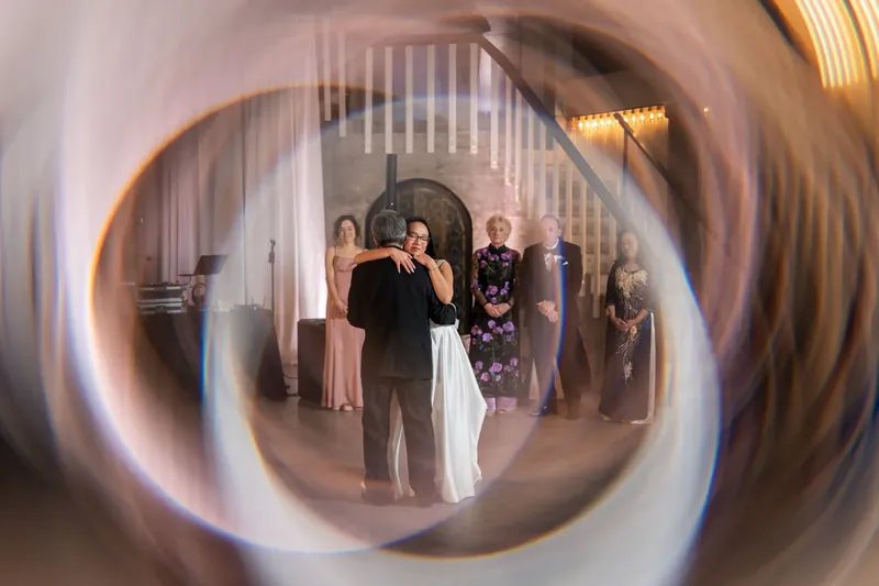 Elizabeth and Jason stand together under ornate archways as wedding guests watch from the Lightner Museum's grand hall.