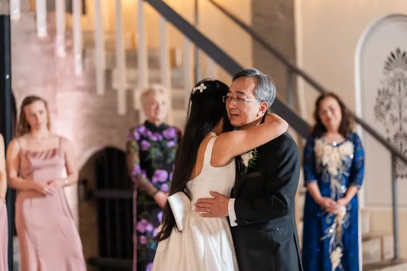 Jason embraces Elizabeth during their first dance as family members look on in the elegant venue.