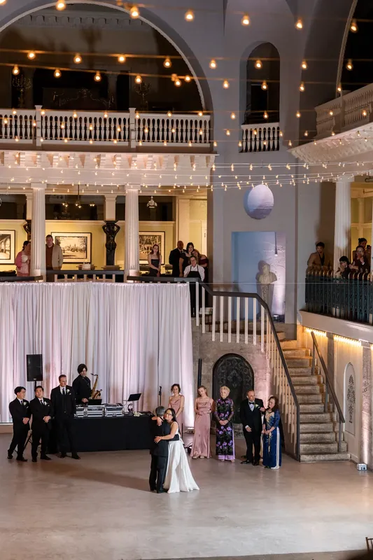 The couple dances in the soaring central atrium of the Lightner Museum, surrounded by architectural balconies and warm