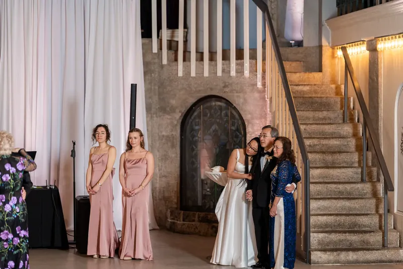 Elizabeth and Jason share a moment while bridesmaids and groomsmen stand nearby in the museum's columned hall.