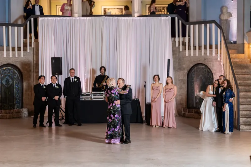 Wedding party members and family gather across the vast museum floor during the reception.