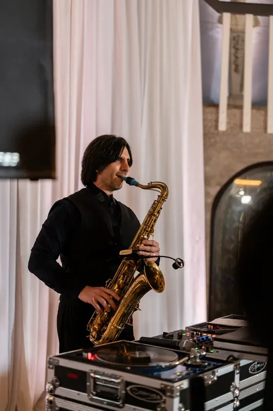 A saxophonist in black performs live music at the celebration.