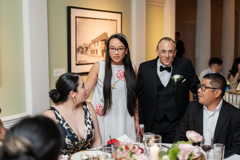 Guests applaud as Jason stands with a woman wearing glasses and a white shawl during the reception.