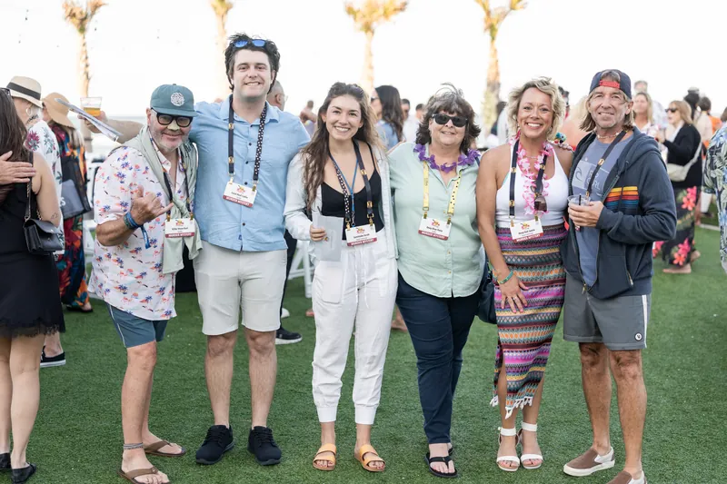 Six guests wearing lanyards and casual attire stand together on the lawn at Embassy Suites St. Augustine Beach.
