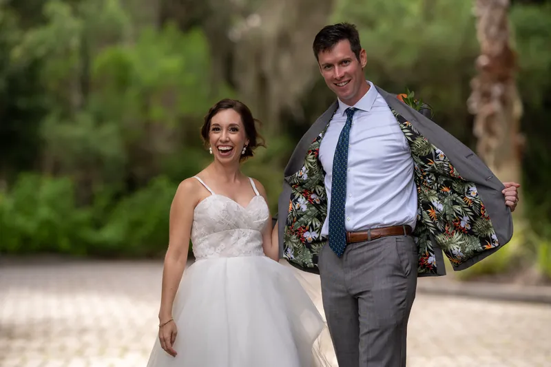 Emma and Kyle stroll outdoors at Oyster Bay Yacht Club, with Kyle displaying a patterned blazer over his grey suit.